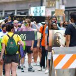 A diverse group of protesters gather peacefully in a city, advocating for justice reform.