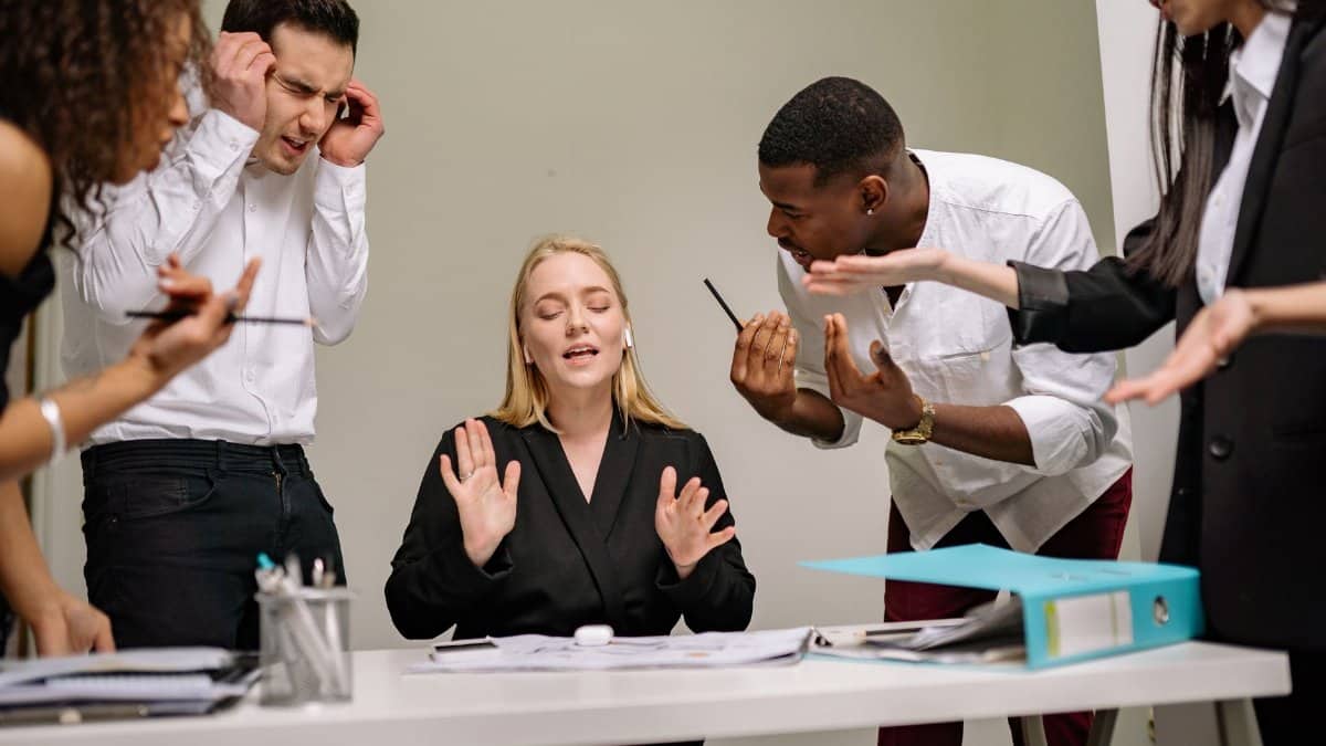 Diverse employees engaged in a heated discussion at a workplace meeting, showcasing stress and tension.
