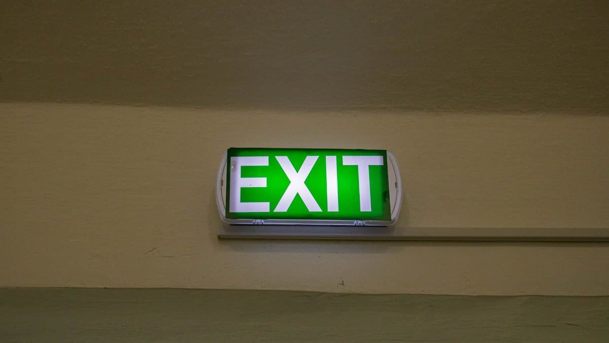 Bright green exit sign mounted on a hallway wall, offering clear direction for emergency evacuation.