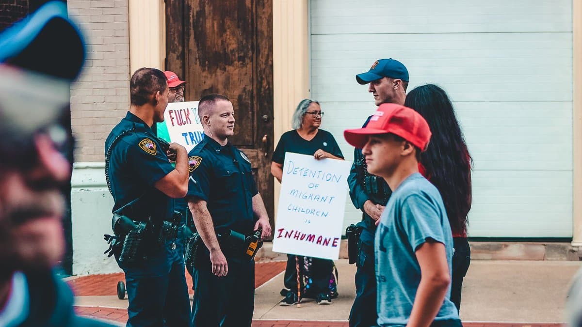 Street protest in Wheeling, WV highlighting immigration issues with signs and police presence.