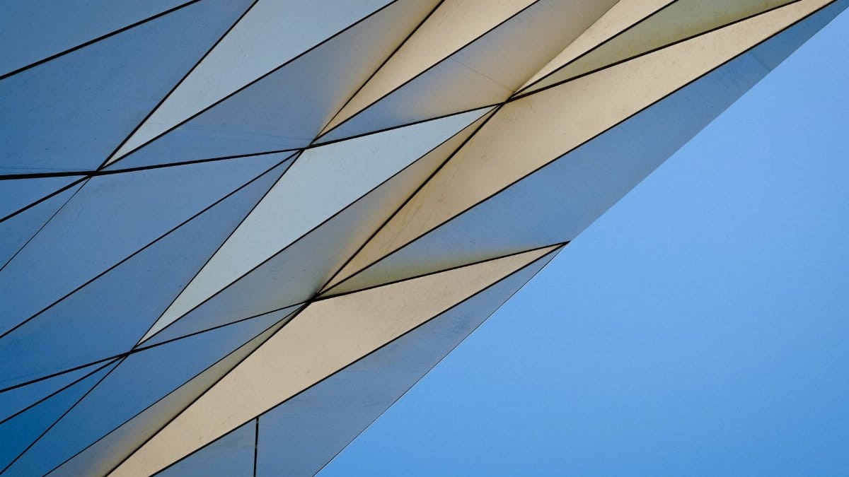 A modern geometric architectural facade against a clear blue sky.