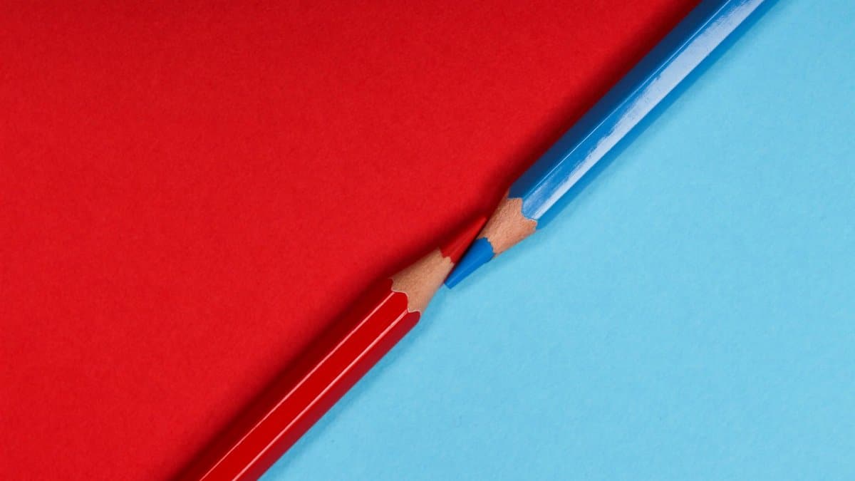 Red and blue colored pencils on matching red and blue paper background, showcasing creativity.