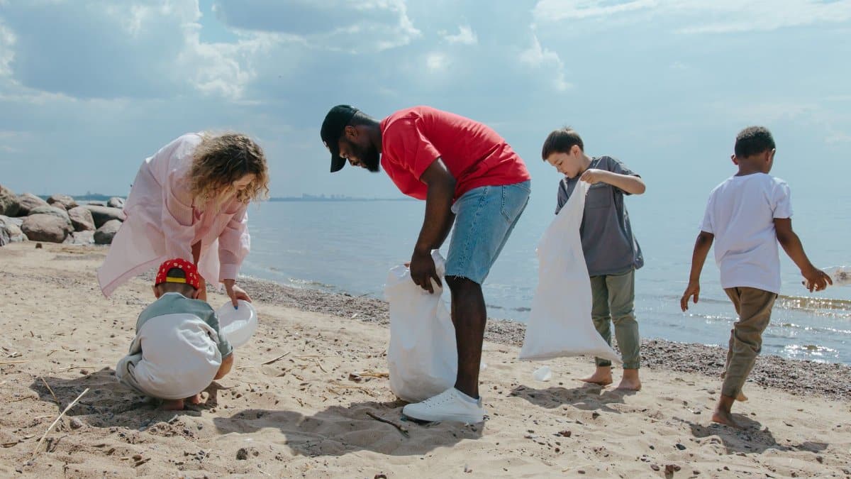 A diverse group participates in a beach cleanup, promoting sustainability and ecology.