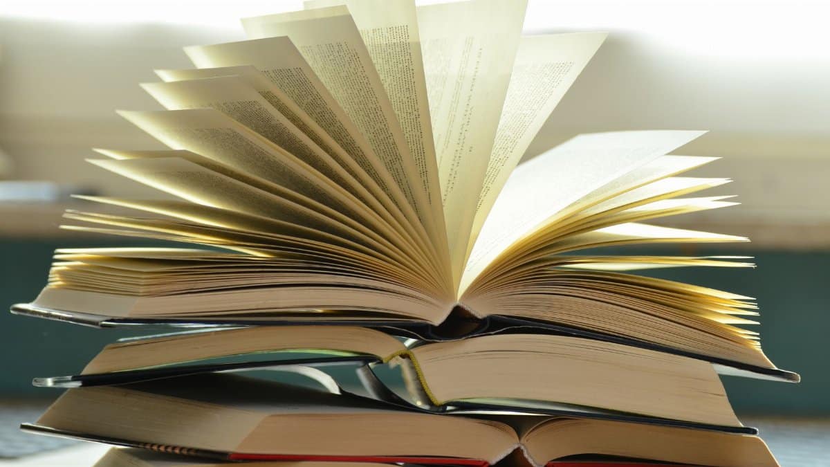 A close-up of a stack of open books with pages fanned out, capturing a study atmosphere.