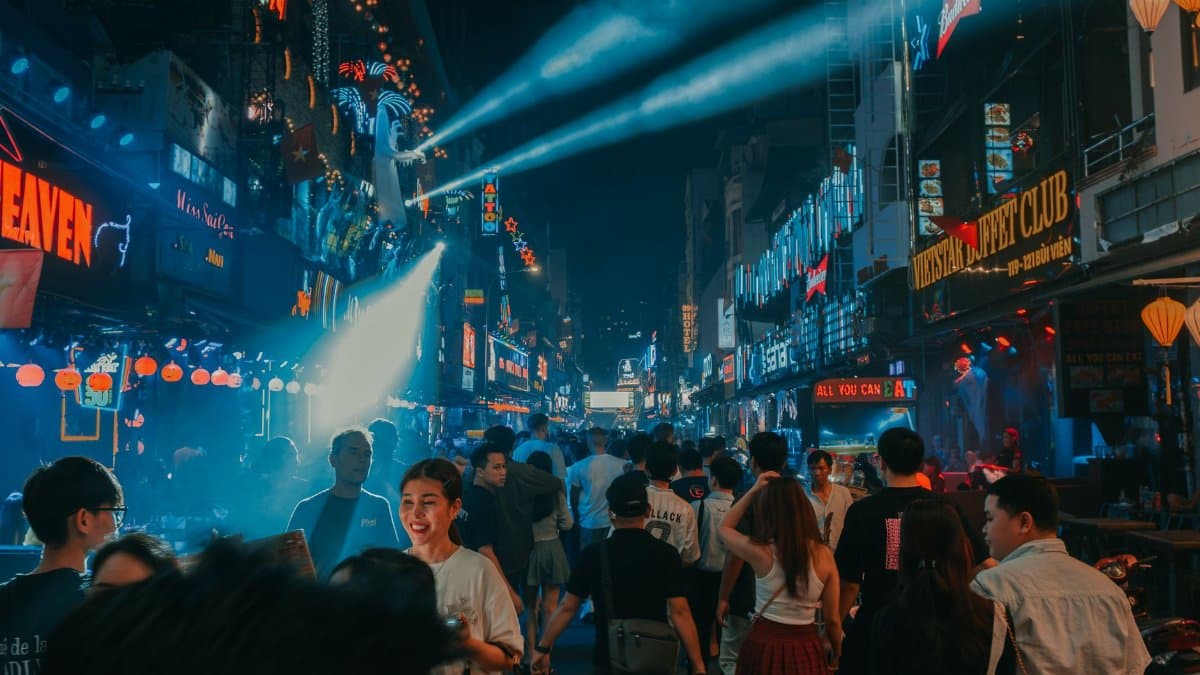 Experience the lively city nightlife with crowds and neon lights illuminating the streets at night.