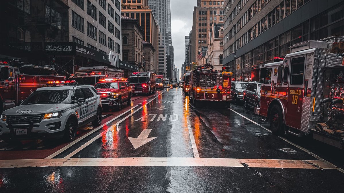 Firetrucks and police cars respond to an emergency on a wet street in New York City.