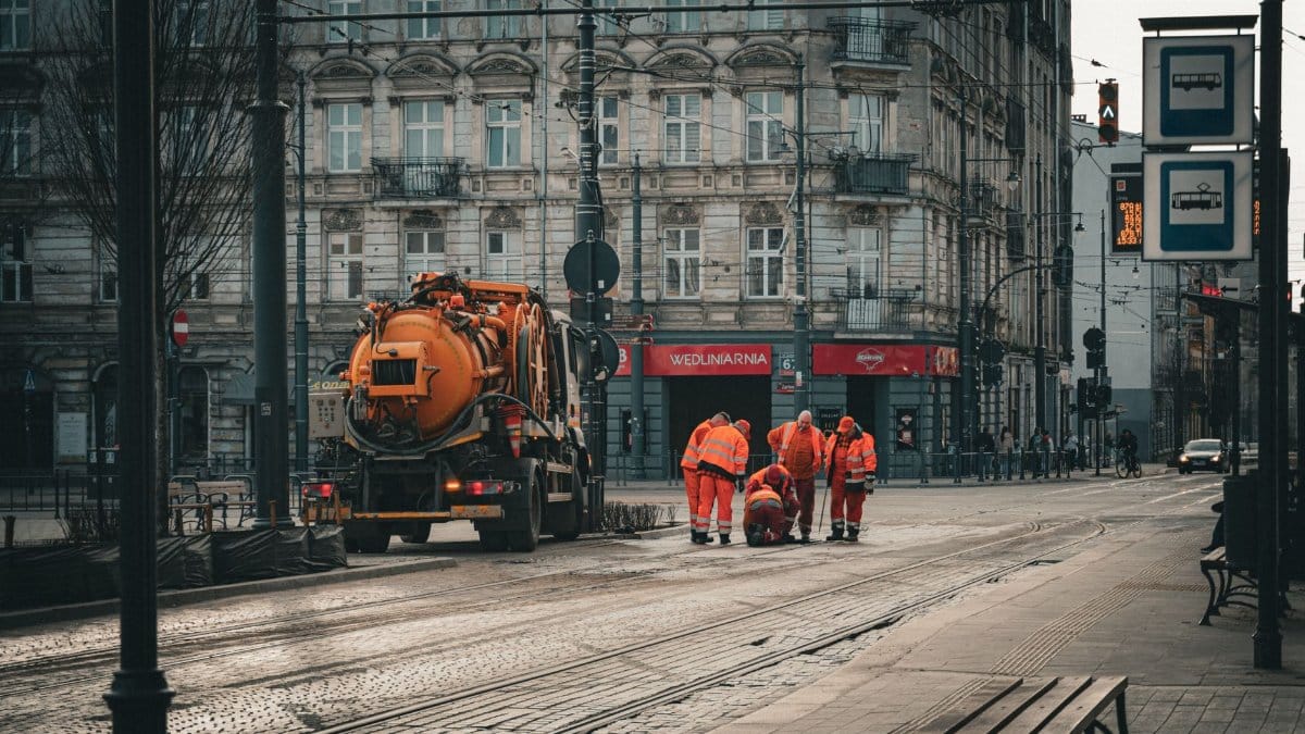 City workers repairing tram tracks on Piotrkowska Street in Łódź, Poland, amidst classic architecture.
