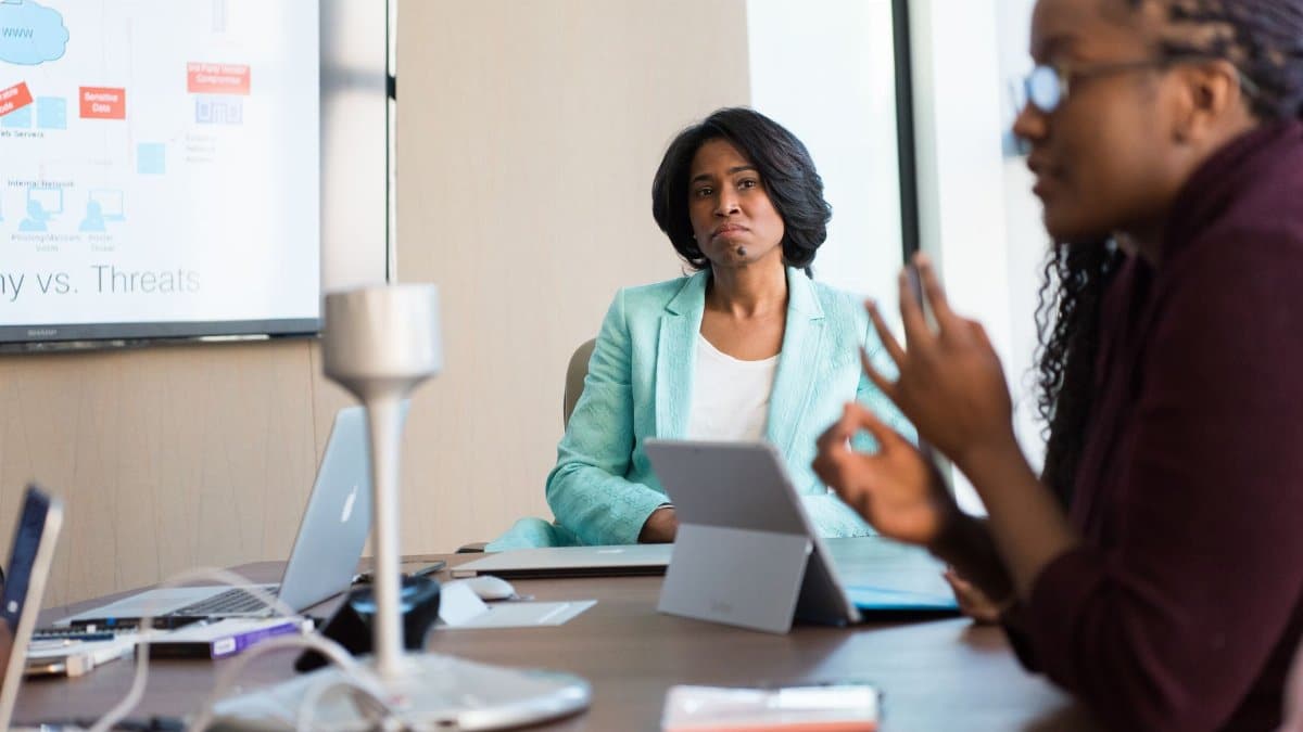 Professional women engaged in a business meeting, discussing strategy with technology at the workplace.