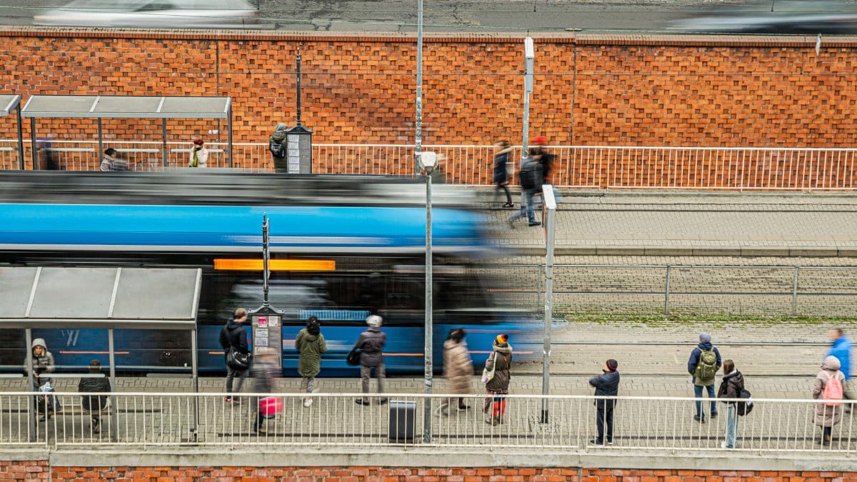 People waiting at a tram station, capturing urban daily life with motion blur.