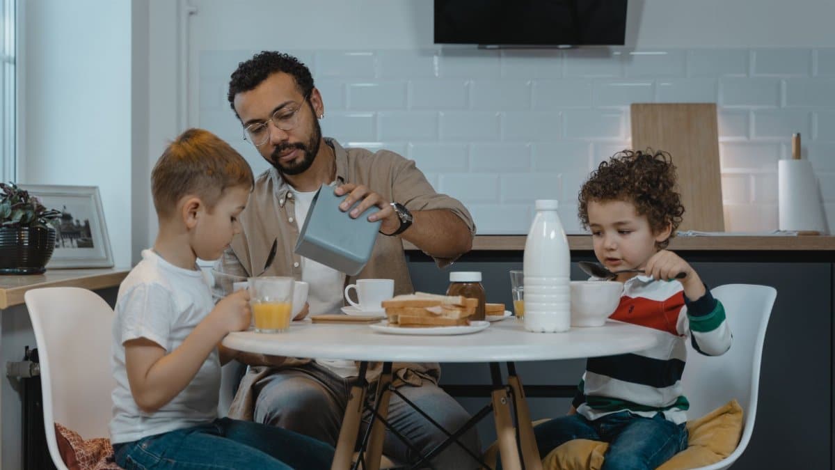 Father and sons enjoying breakfast together at a modern kitchen table.