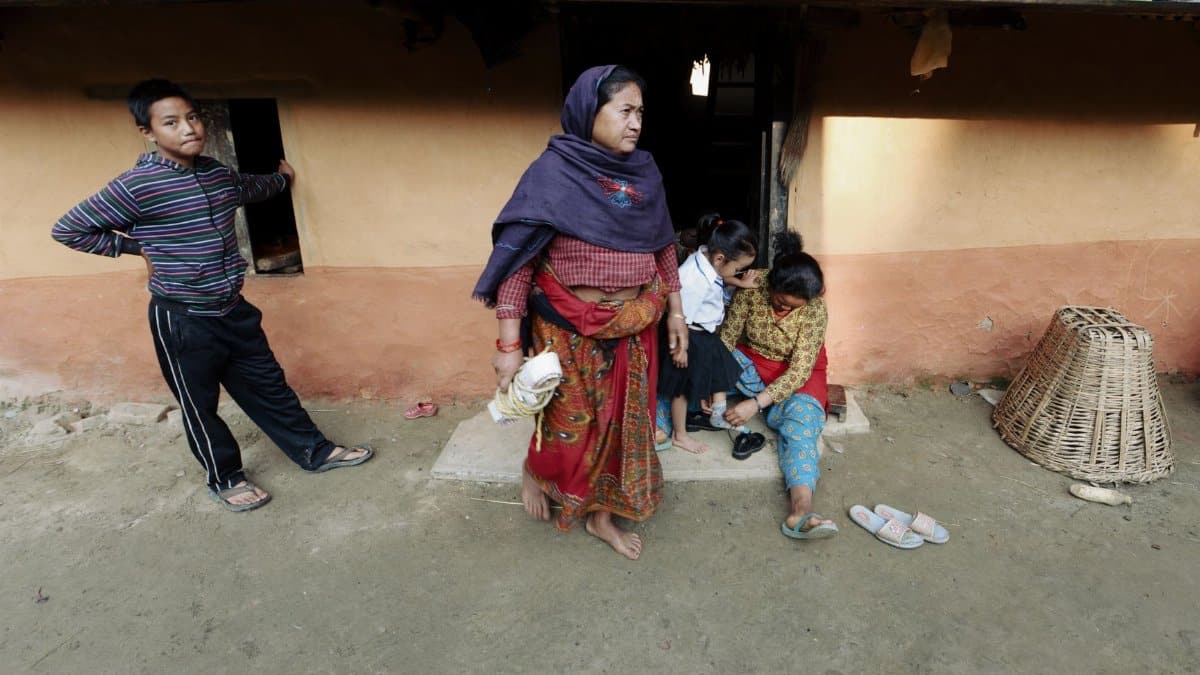 A family in traditional attire outside their rural home, showcasing everyday life.