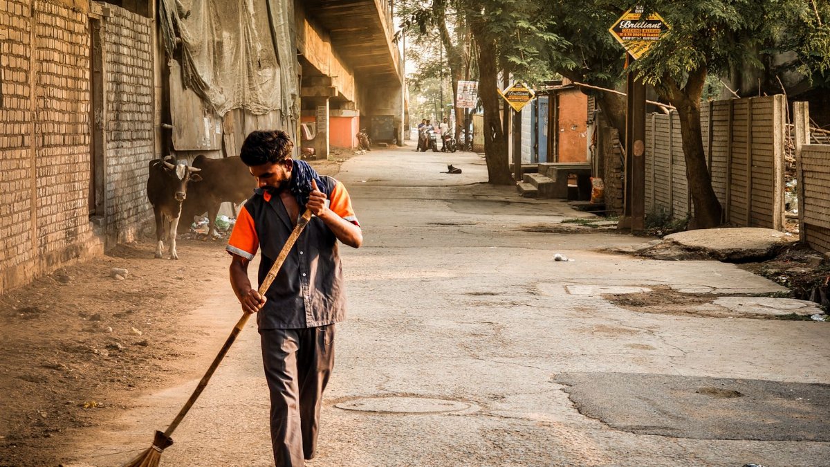 A street sweeper cleans a quiet urban street at sunrise, embodying everyday life and city sanitation.