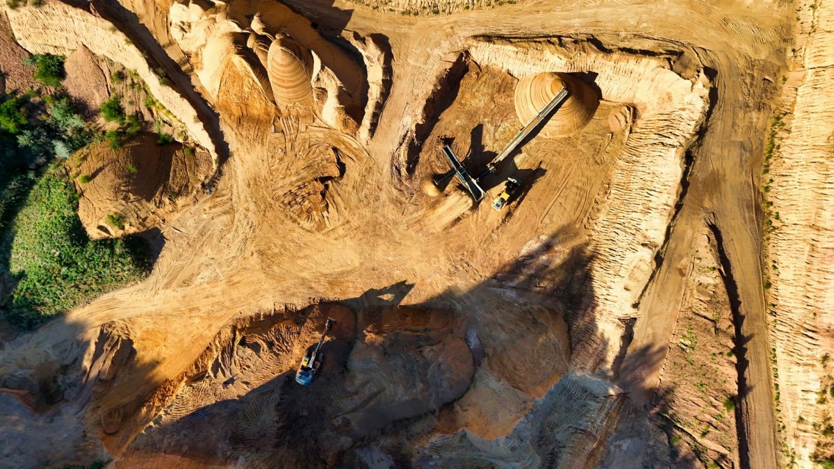 Stunning aerial photo showcasing a large open pit mining operation under sunny conditions.
