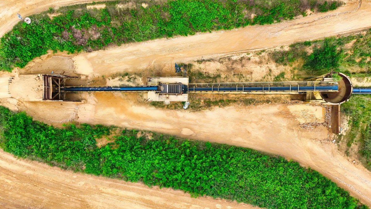 Aerial image of an industrial conveyor system between green fields.