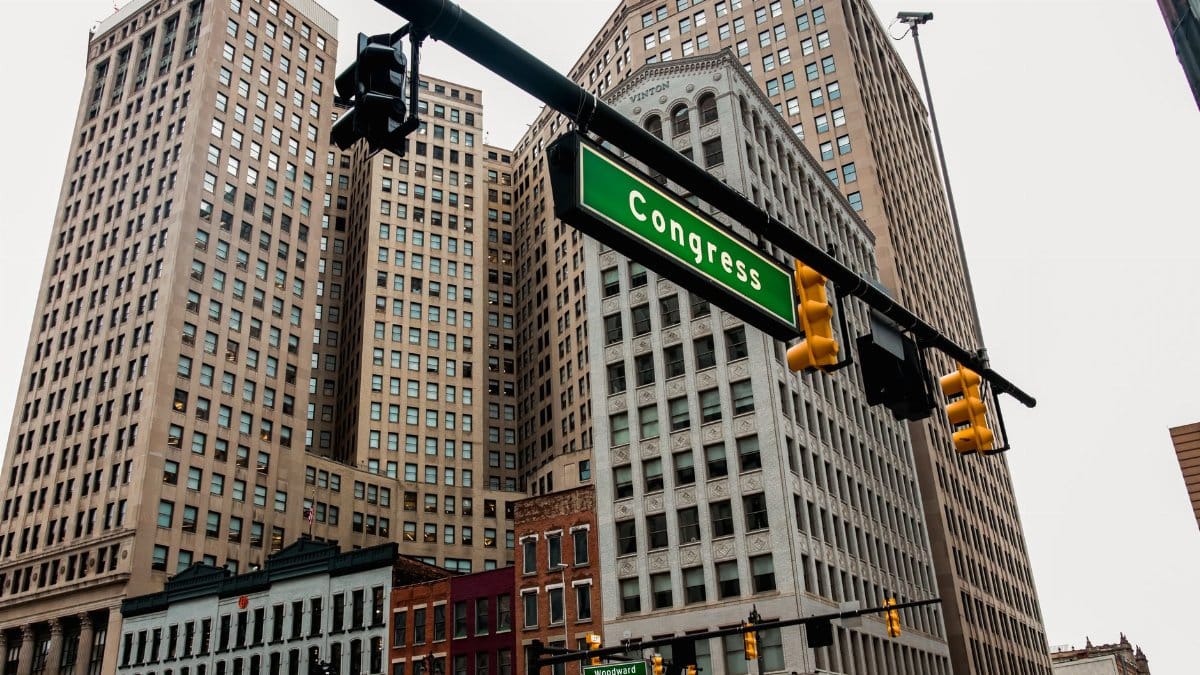 Low-angle view of Detroit skyscrapers and Congress street sign, capturing the urban essence of downtown.