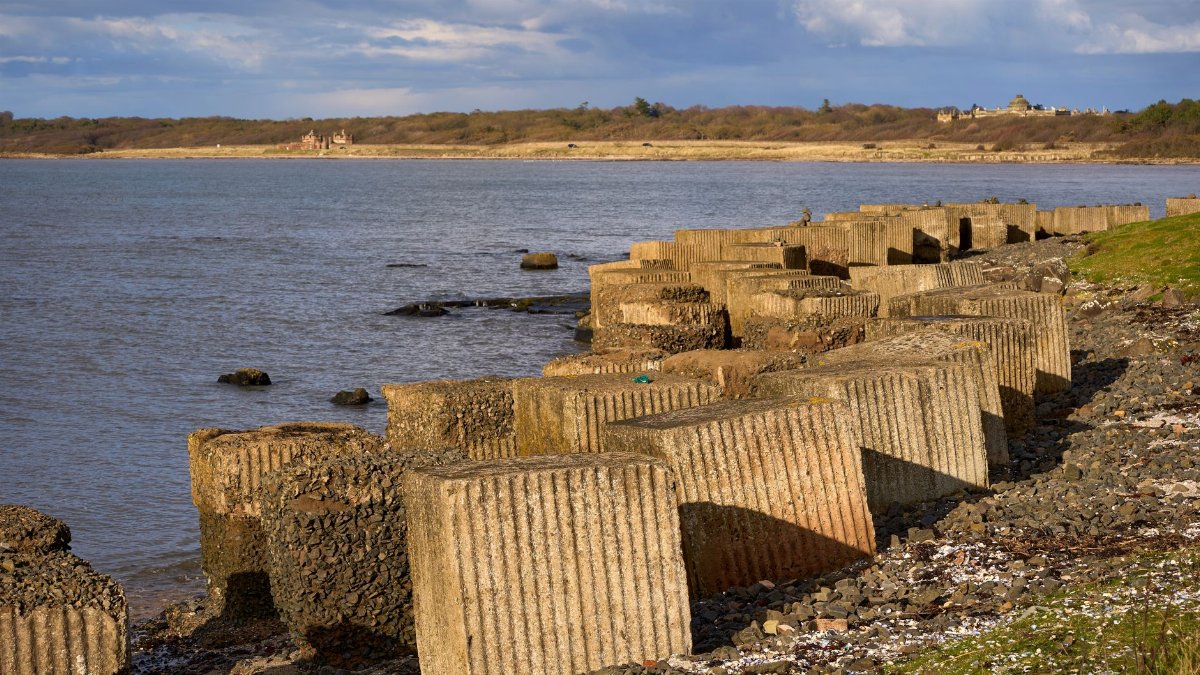 Concrete coastal defenses along the shore of Gosford Bay in East Lothian, Scotland, during spring.