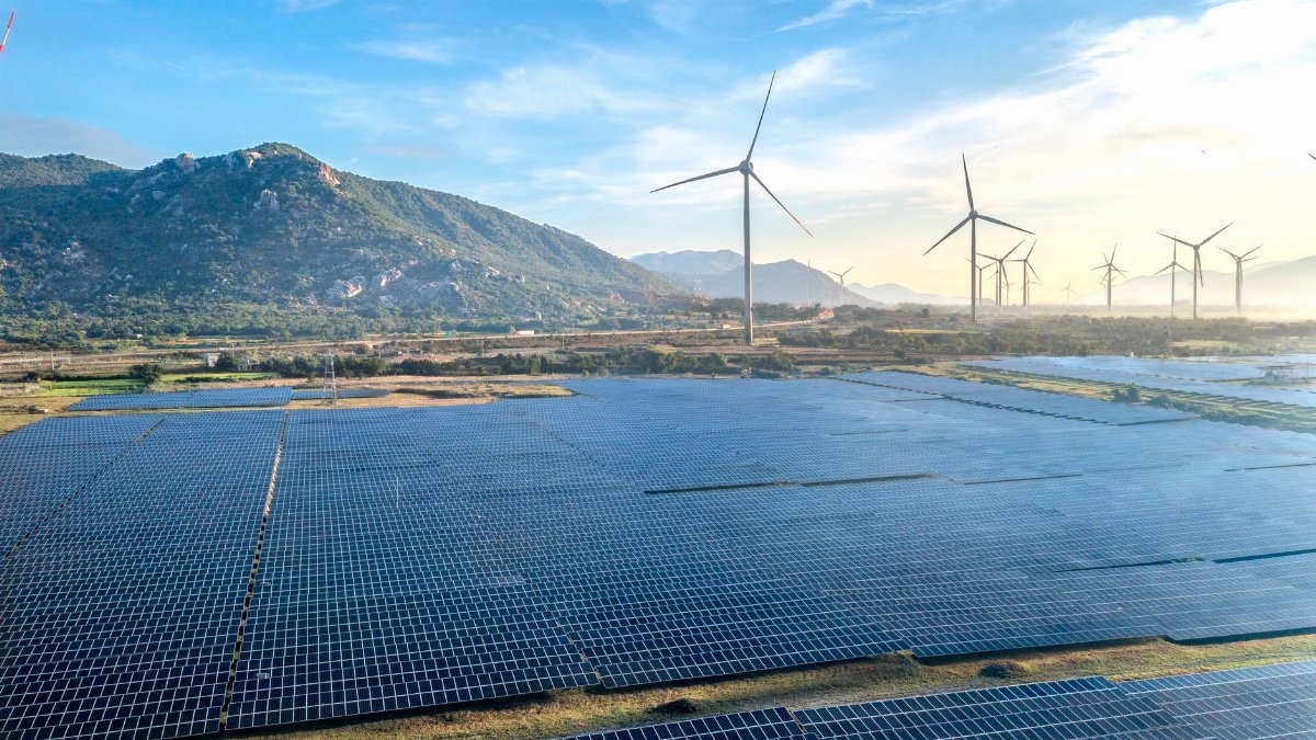 Aerial view of a solar and wind energy farm set against Vietnam's scenic landscape.