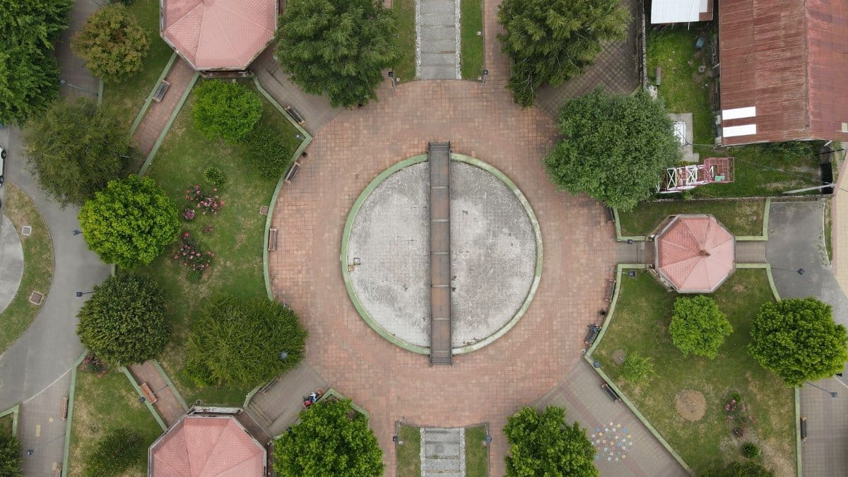 Top-down view of a circular plaza with pathways and greenery in a city park.
