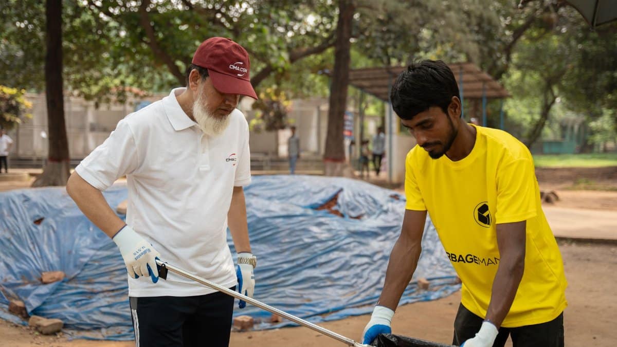 Two volunteers picking up litter in a park during a community clean-up event.
