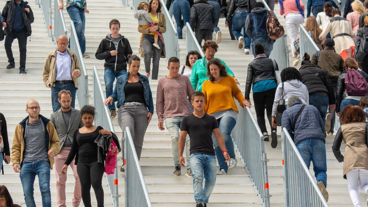 A diverse crowd of people walking downstairs in a bustling urban environment, showcasing everyday life.