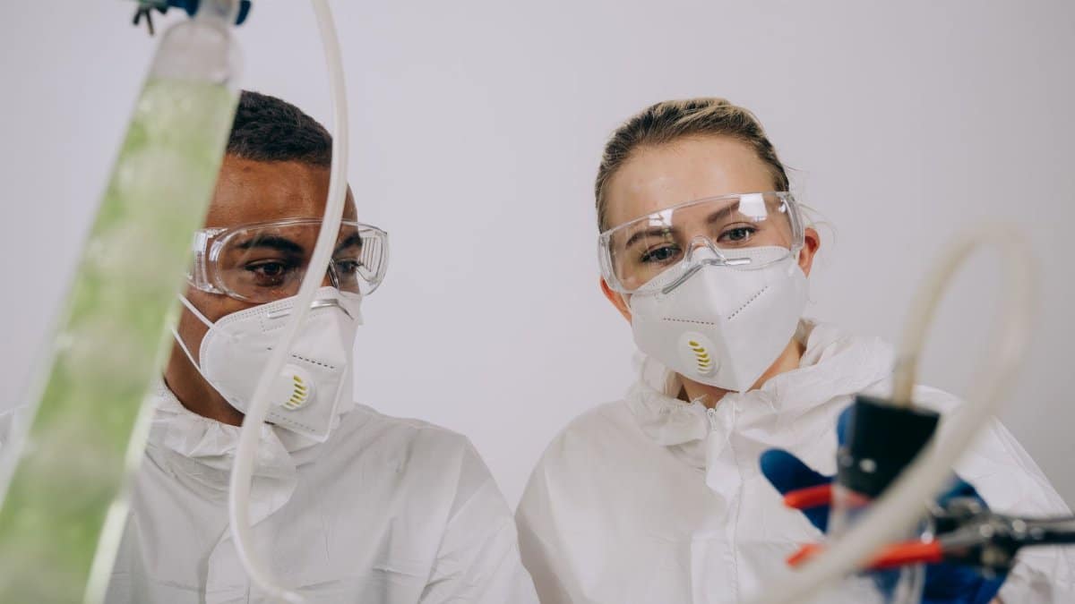 Two scientists conducting research in a lab with protective equipment.
