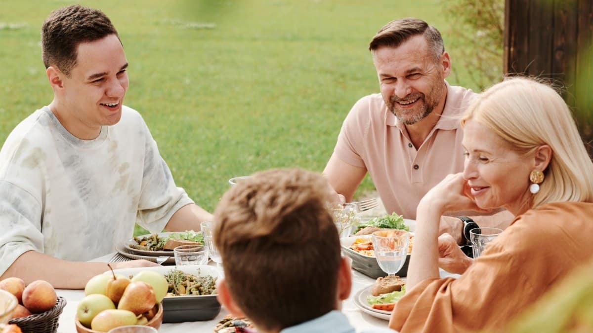 A cheerful family enjoying a meal together outdoors, sharing laughter and warmth.