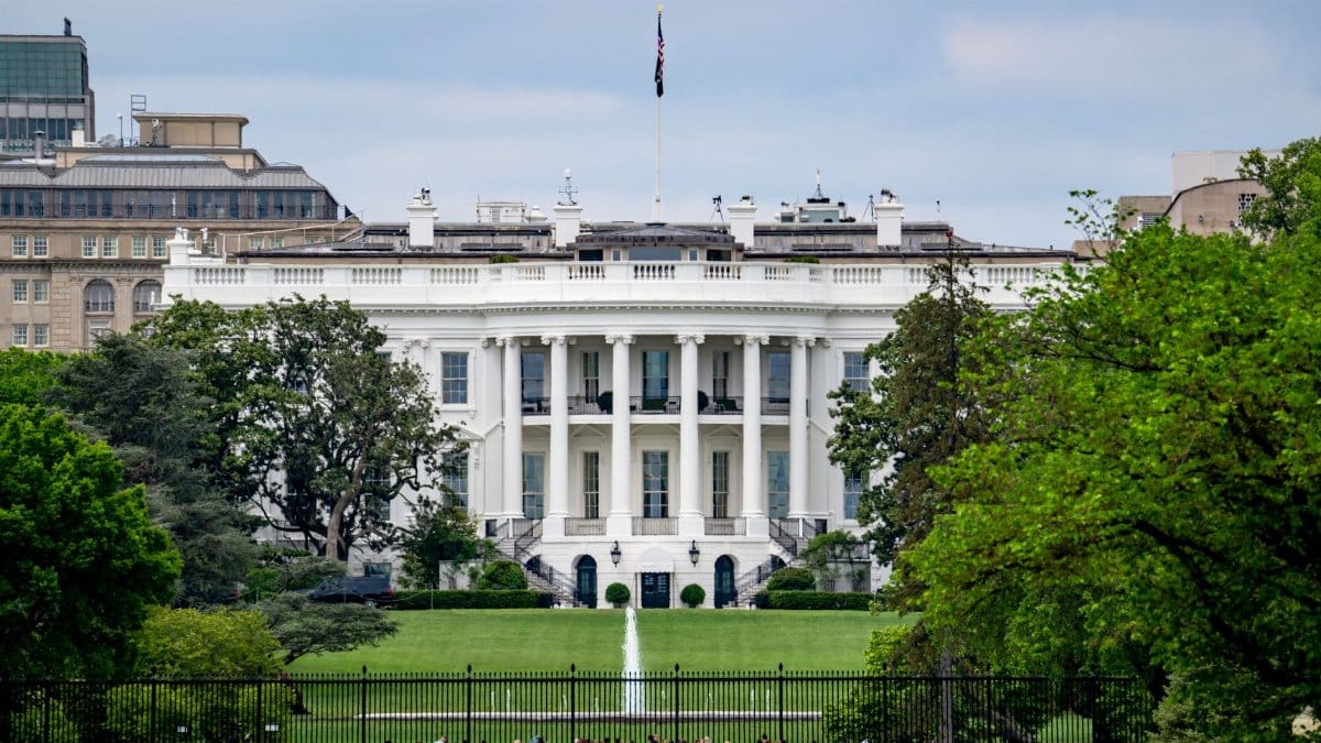 A scenic view of The White House, a renowned landmark in Washington, DC, surrounded by greenery and tourists.