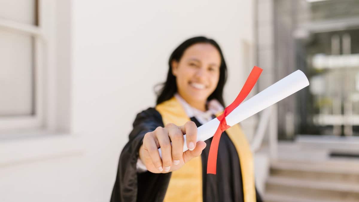 A happy graduate proudly displays her diploma in an outdoor setting, symbolizing achievement.