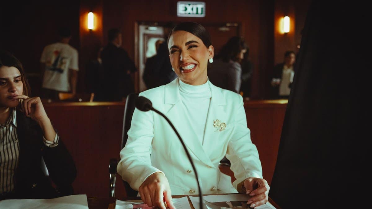 Smiling woman in white suit in a courtroom, conveying professionalism and confidence.