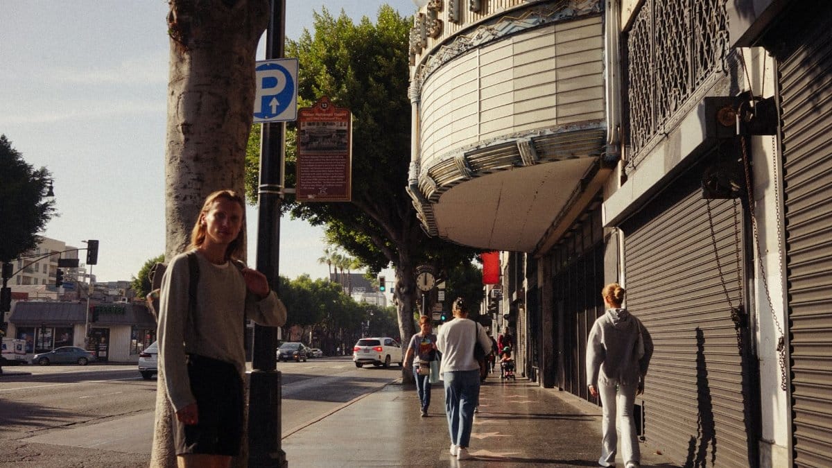People strolling by a classic theater in an urban street setting, capturing local culture.