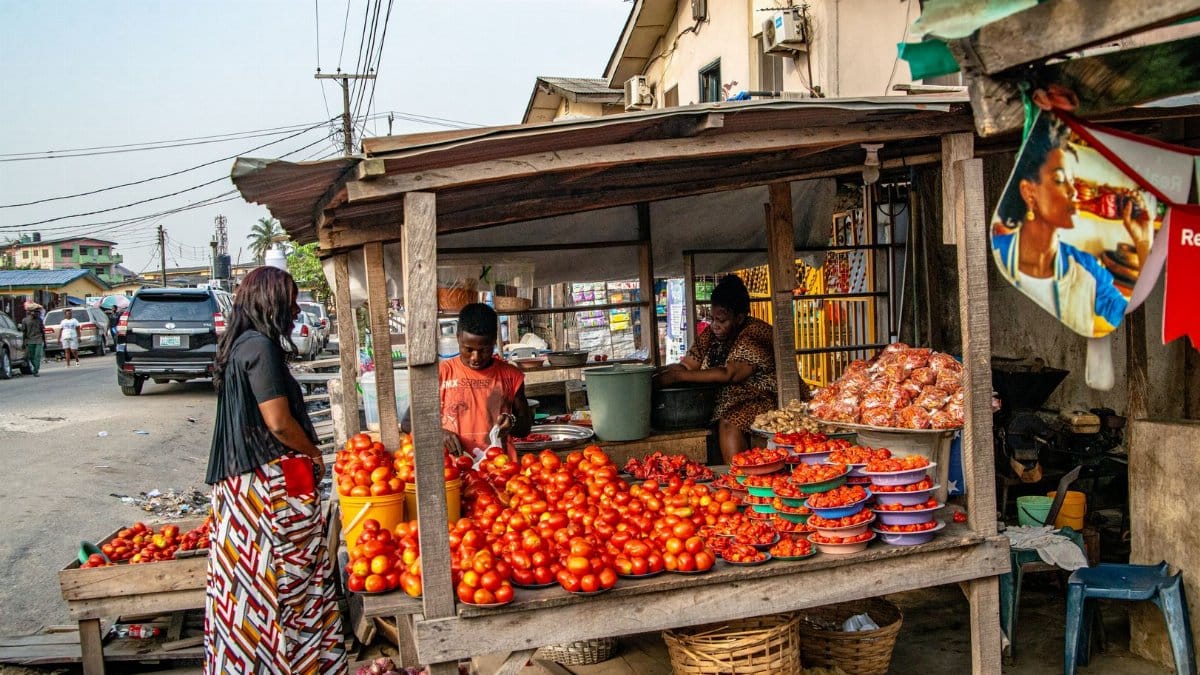 A bustling street market scene showcasing fresh tomatoes and local vendors in a vibrant urban setting.