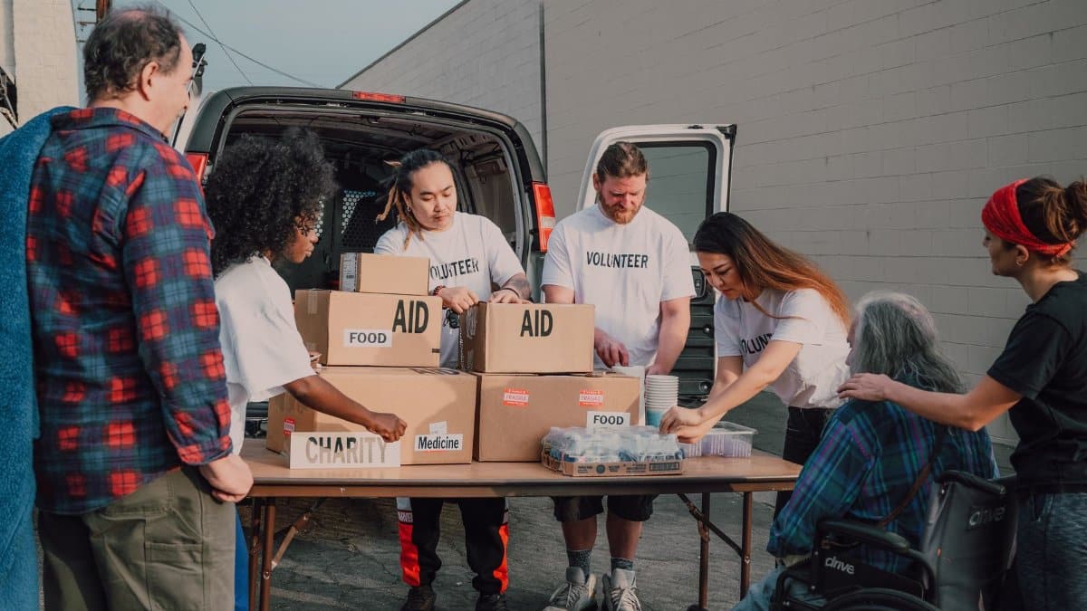 Group of diverse volunteers organizing aid packages outdoors for a charity event.