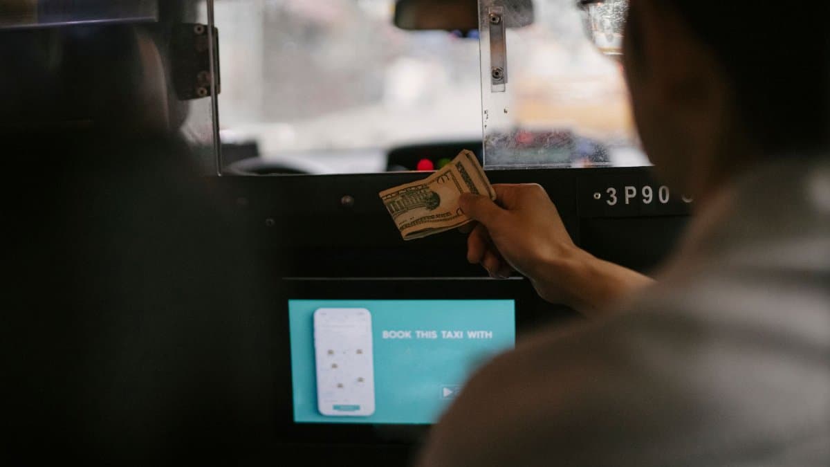 Back view of taxi car interior with tablet screen located near passenger seat and client paying for ride