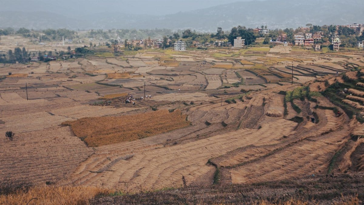 Expansive aerial view of terraced fields and a nearby town under a clear sky, showcasing rural agriculture.