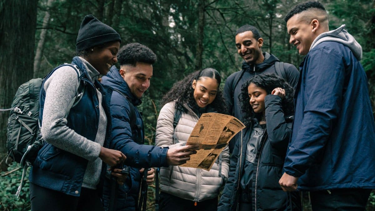Diverse group of friends hiking together, planning their adventure in a lush forest.
