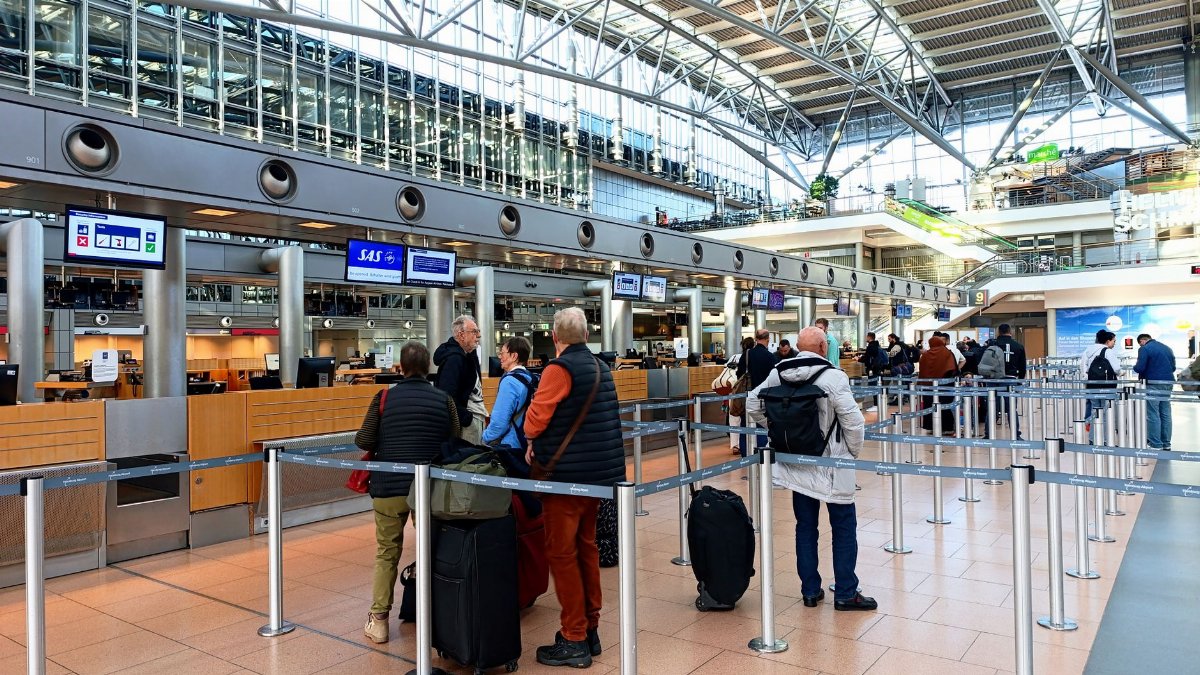 Travelers in line at Hamburg Airport's check-in counters, showcasing modern architecture.