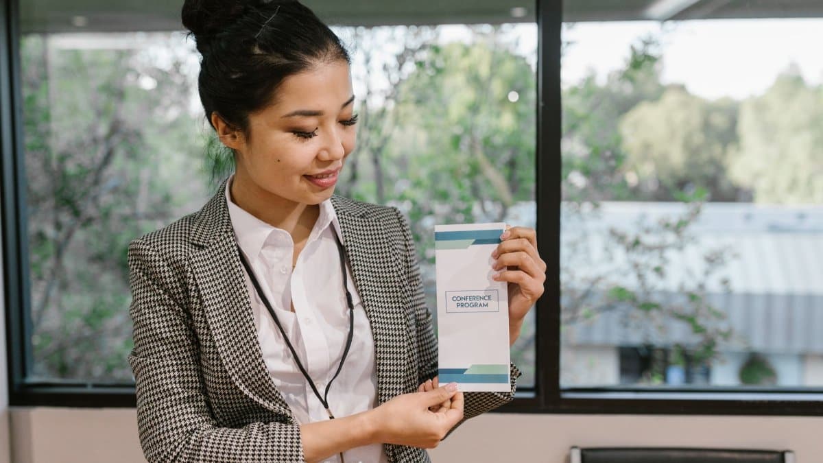 Young professional woman holding a conference program brochure indoors.