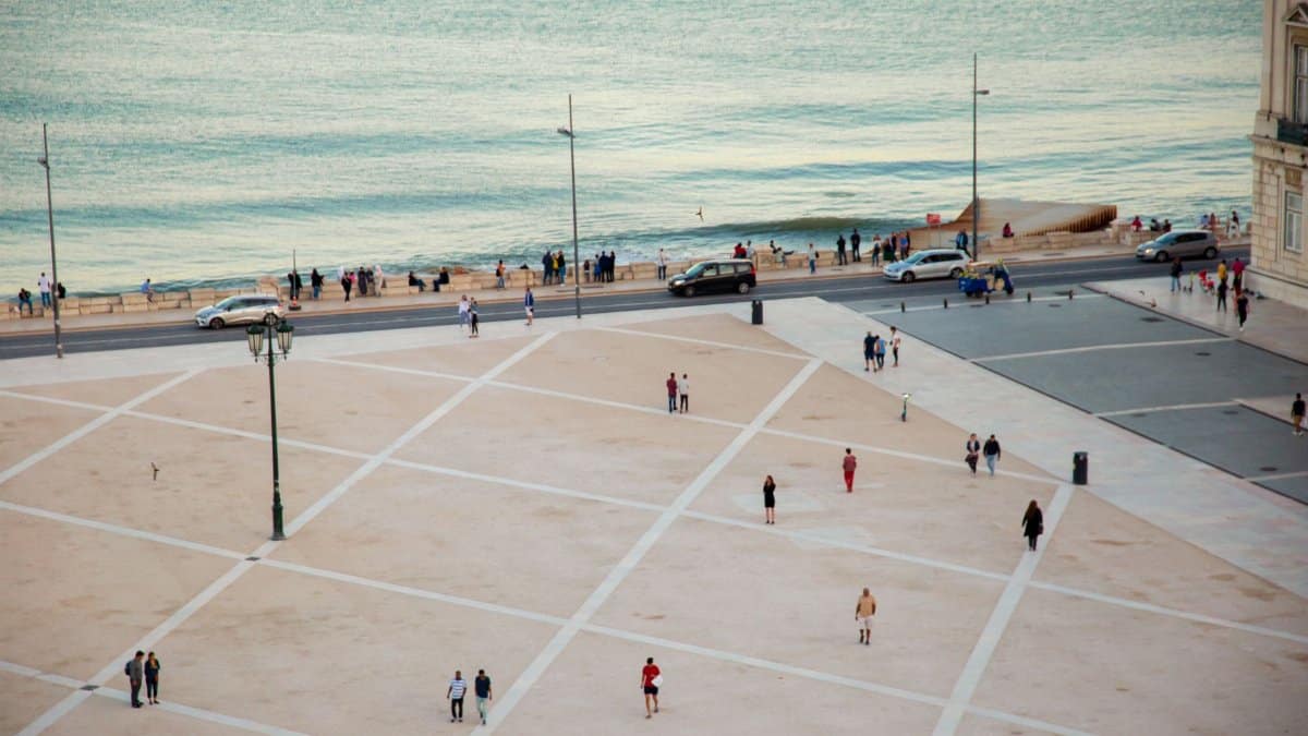 High angle citizens strolling on vast public square near rippling river located in coastal city in twilight