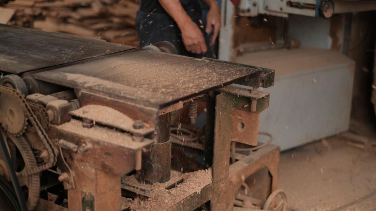 Carpenter using a sawdust-producing machine in a woodworking shop.