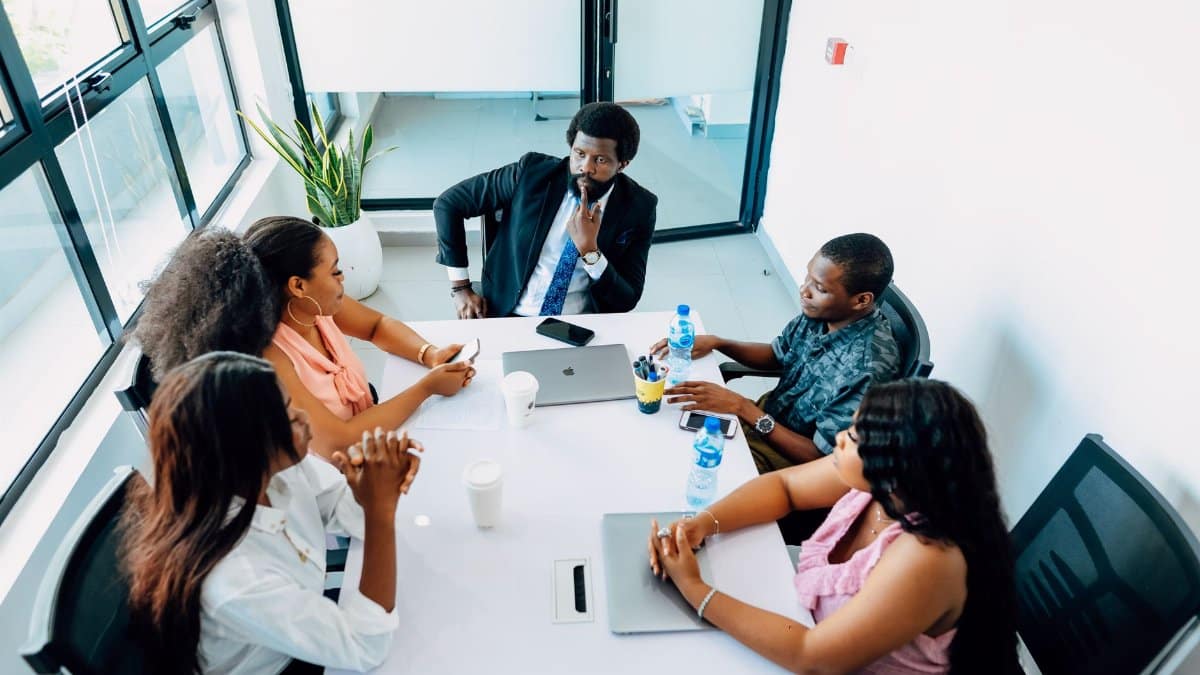 A group of professionals engaged in a business discussion around a table in a Lagos office.