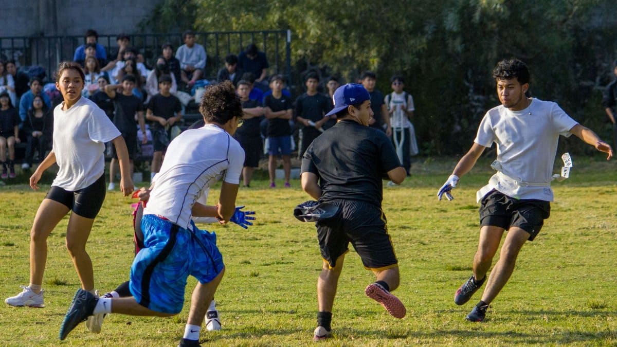 A group of college students engaged in an energetic outdoor sports game on a sunny day.