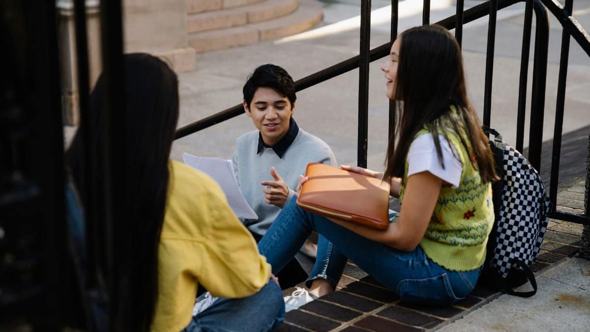 Three college students sitting and talking outdoors on campus.