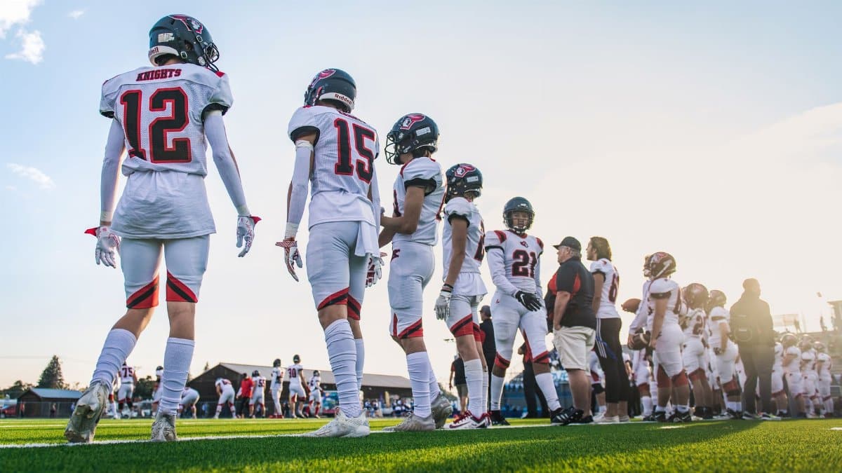 A high school football team lines up on the field, ready for their match.