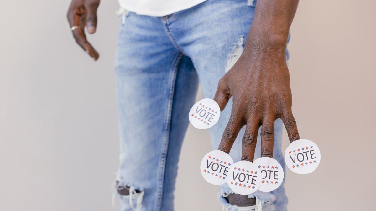 Close-up of a person holding vote stickers, emphasizing the importance of voting.