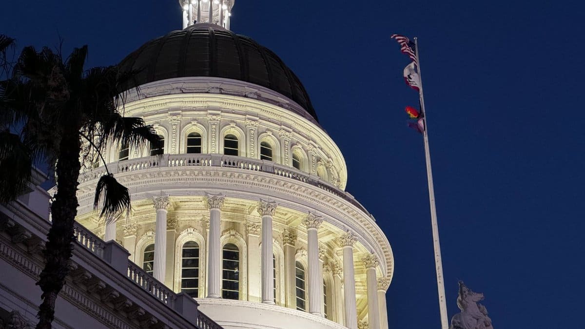 Illuminated California State Capitol dome with flags at dusk, Sacramento, USA.