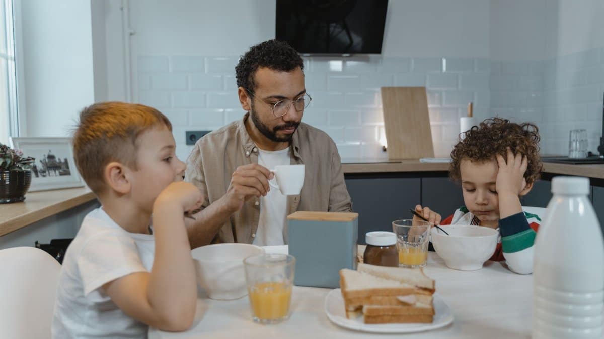 A father and his two young sons sharing a breakfast moment at home.