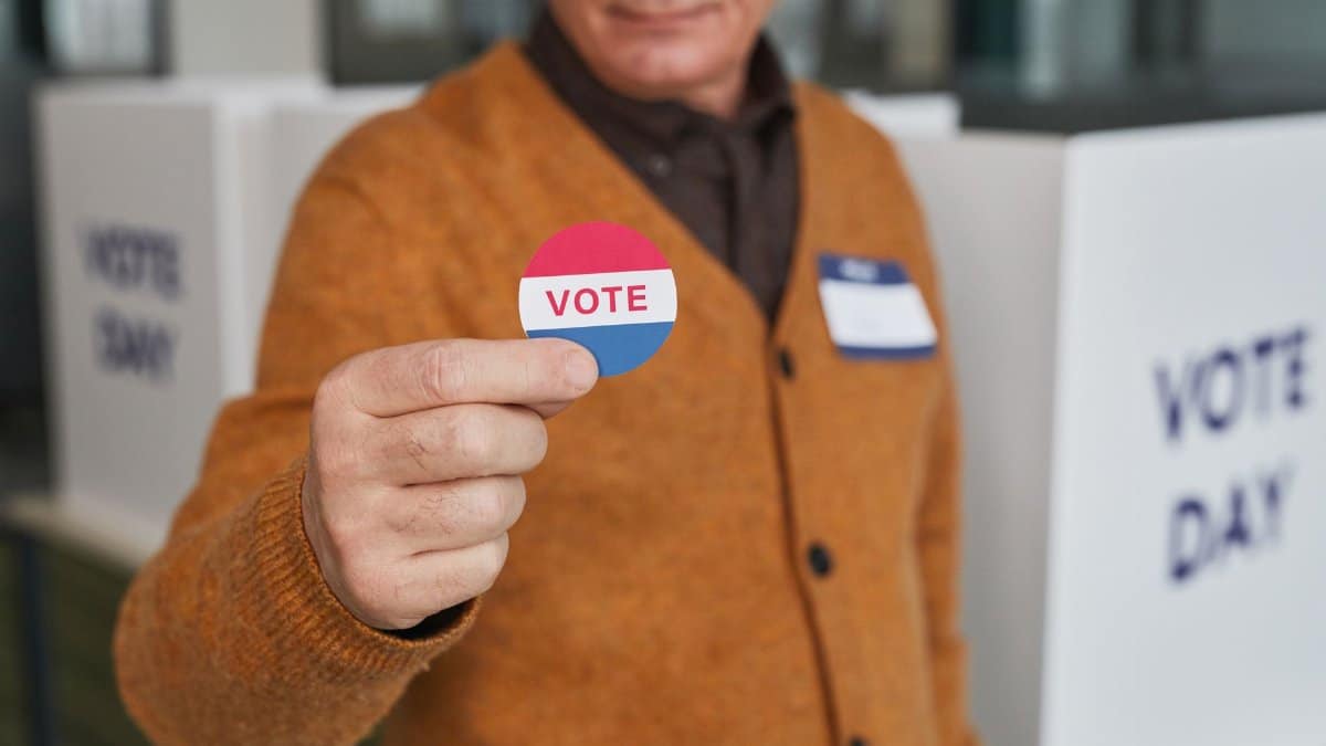 A senior adult holding a vote sticker inside a polling booth during election day.