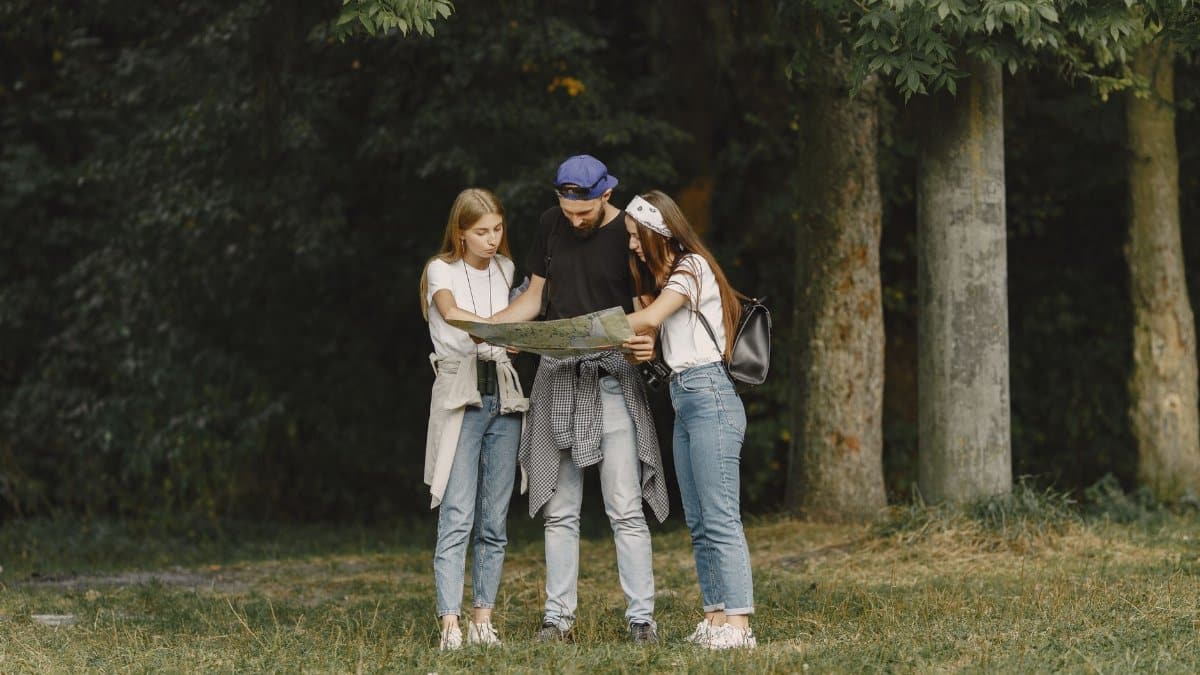 Three friends studying a map during a hiking trip in a lush forest.