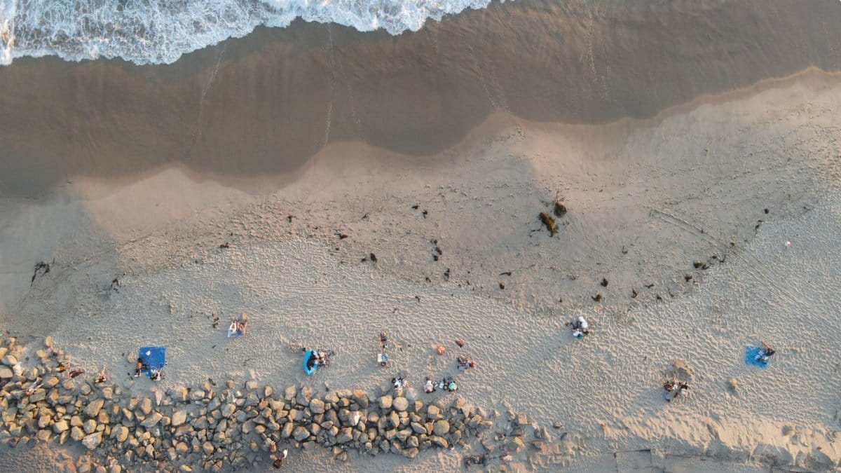 Drone shot of people relaxing on Huntington Beach, California's sandy coast.