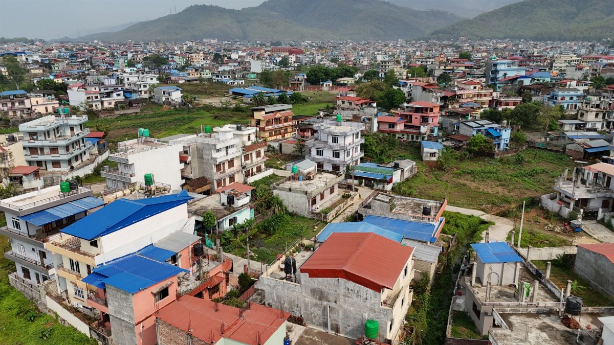 Aerial shot of residential areas and distant mountains in Nepal, showcasing urban landscape.